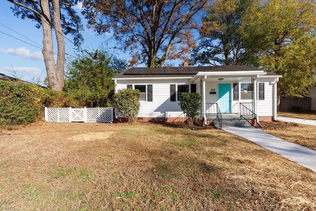 view of front of home with a front yard, solar panels, and covered porch