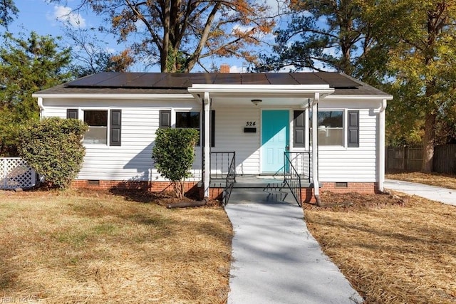 bungalow-style house featuring solar panels, a porch, and a front lawn