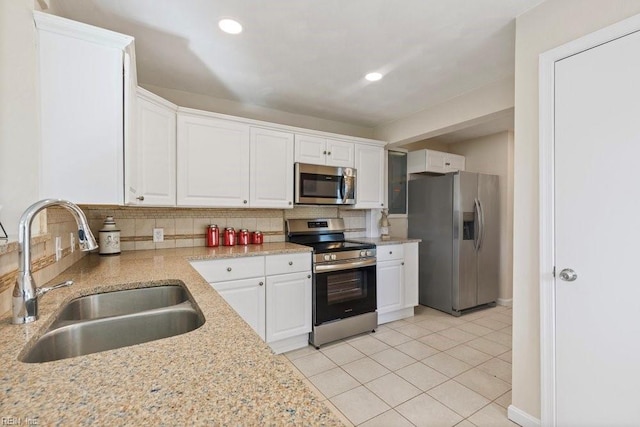 kitchen with appliances with stainless steel finishes, backsplash, white cabinetry, and sink