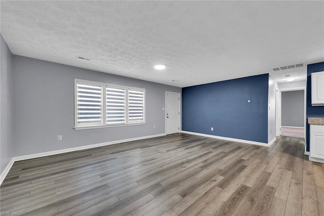 unfurnished room featuring a textured ceiling and light hardwood / wood-style flooring