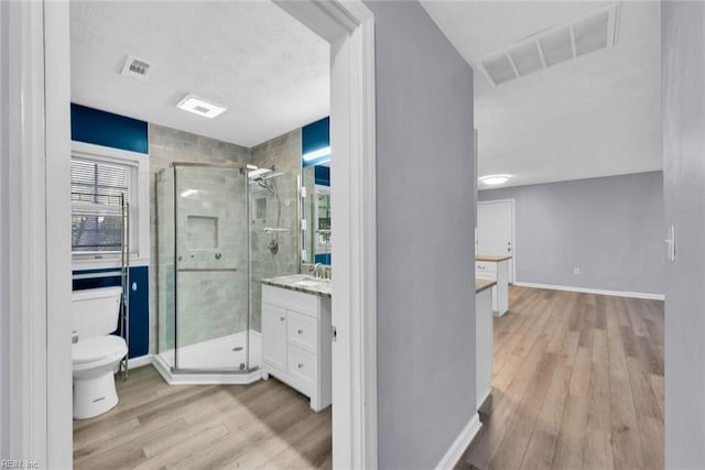 bathroom featuring vanity, hardwood / wood-style flooring, toilet, and a shower with shower door