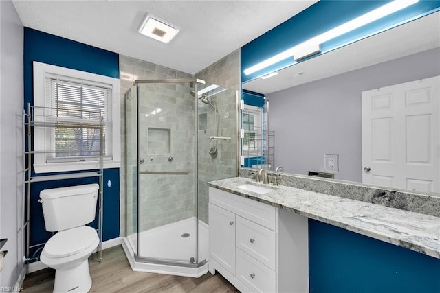 bathroom featuring a shower with door, vanity, wood-type flooring, and toilet