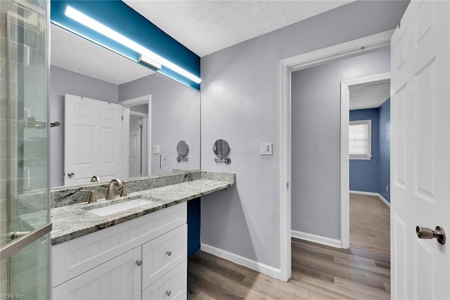 bathroom featuring vanity, an enclosed shower, wood-type flooring, and a textured ceiling