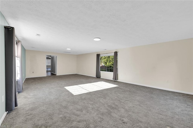 unfurnished room with dark colored carpet and a textured ceiling