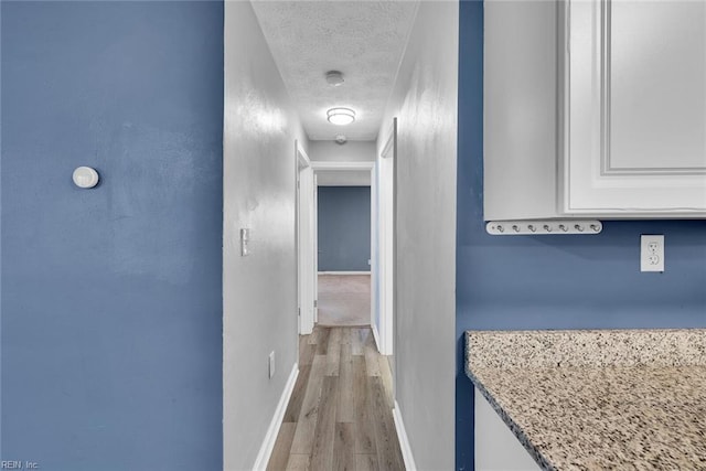 hallway featuring light hardwood / wood-style flooring and a textured ceiling