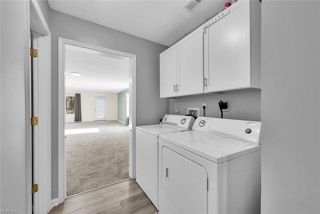 washroom featuring light hardwood / wood-style floors, cabinets, independent washer and dryer, and a textured ceiling