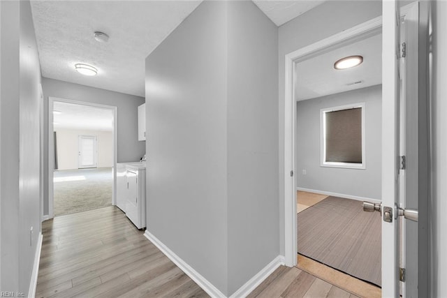 hallway featuring washing machine and dryer and light hardwood / wood-style flooring