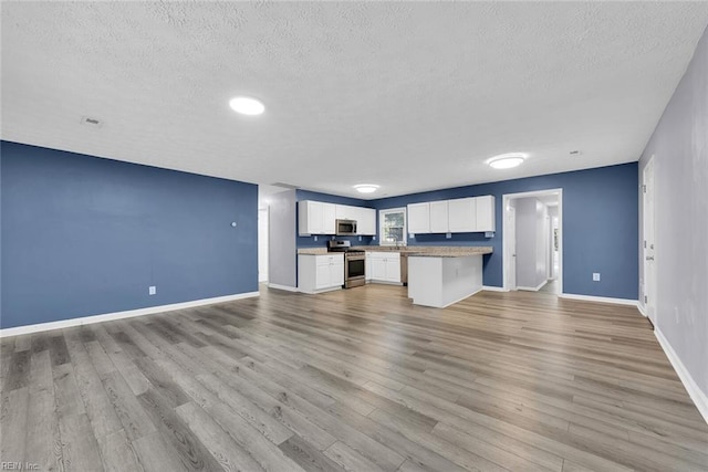 unfurnished living room featuring a textured ceiling and light hardwood / wood-style flooring