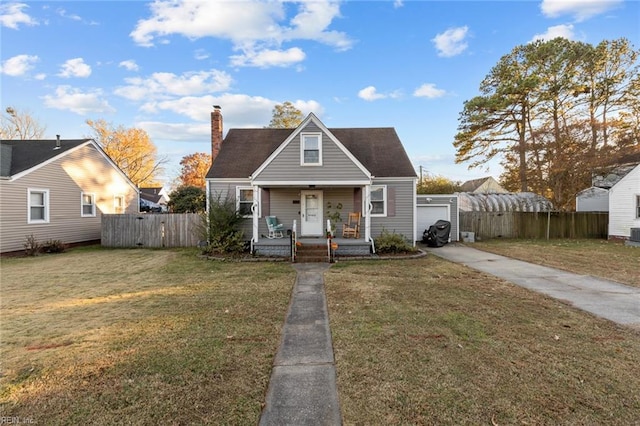 bungalow-style house with covered porch, a garage, an outdoor structure, and a front lawn