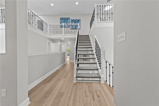 stairs with a towering ceiling and hardwood / wood-style flooring