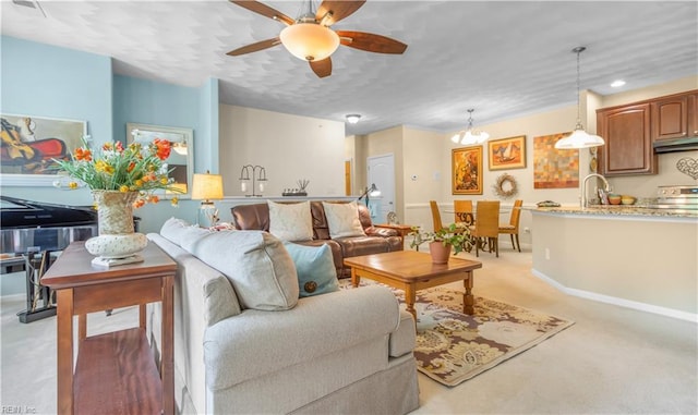 carpeted living room with ceiling fan with notable chandelier and sink