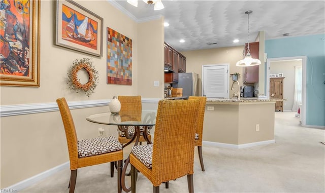 carpeted dining room featuring ornamental molding and sink