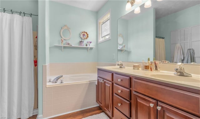 bathroom with hardwood / wood-style floors, vanity, and a relaxing tiled tub