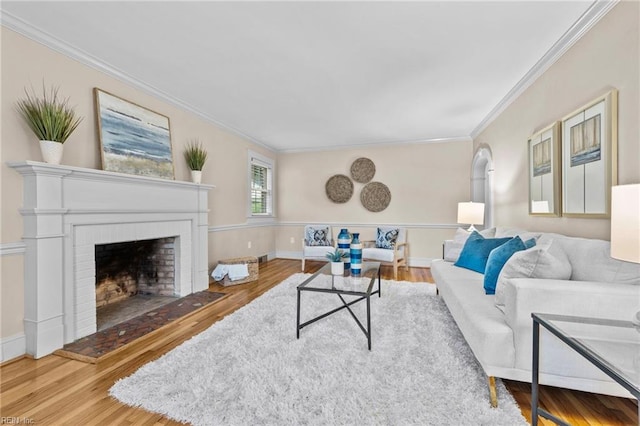 living room with crown molding, wood-type flooring, and a brick fireplace