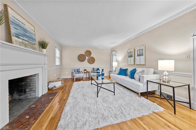 living room featuring hardwood / wood-style flooring, crown molding, and a fireplace