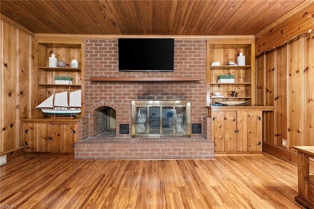 unfurnished living room featuring wood ceiling, built in features, light hardwood / wood-style floors, and a brick fireplace