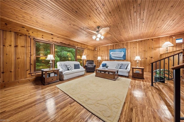 living room featuring hardwood / wood-style flooring, ceiling fan, wood walls, and wooden ceiling