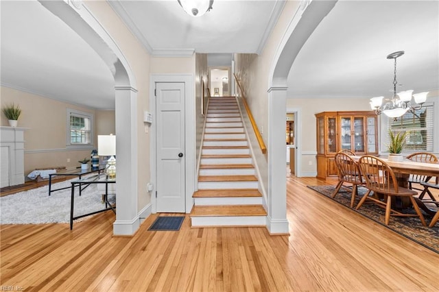 stairway featuring a chandelier, plenty of natural light, ornamental molding, and hardwood / wood-style flooring