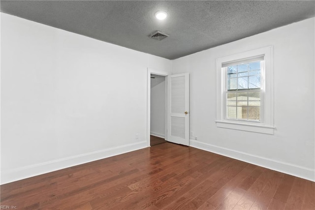 empty room with a textured ceiling and dark hardwood / wood-style flooring