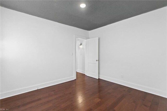 empty room with a textured ceiling and dark wood-type flooring