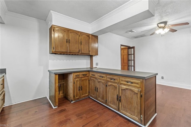 kitchen featuring kitchen peninsula, a textured ceiling, ceiling fan, crown molding, and dark wood-type flooring