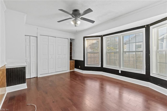 unfurnished bedroom with ornamental molding, ceiling fan, and dark wood-type flooring