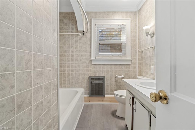 bathroom featuring heating unit, crown molding, vanity, tile walls, and hardwood / wood-style flooring