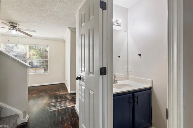 bathroom featuring vanity, hardwood / wood-style flooring, ceiling fan, ornamental molding, and a textured ceiling