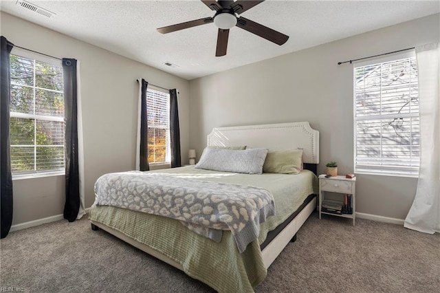 carpeted bedroom featuring ceiling fan, a textured ceiling, and multiple windows