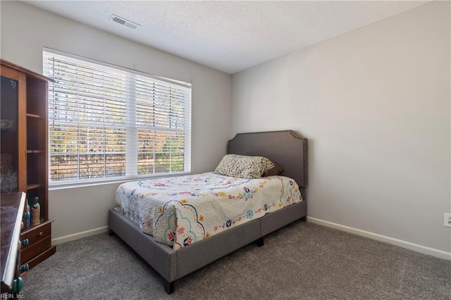 bedroom with a textured ceiling and dark colored carpet