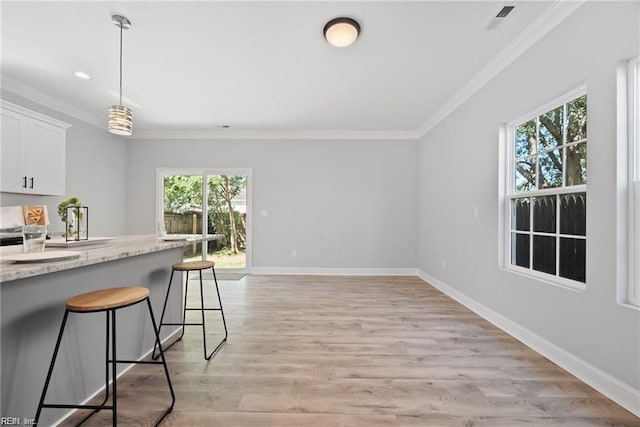 kitchen with a breakfast bar, white cabinetry, light hardwood / wood-style flooring, and a wealth of natural light