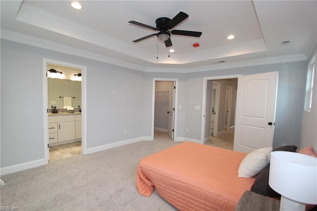 carpeted bedroom featuring ensuite bath, a raised ceiling, crown molding, a walk in closet, and a closet