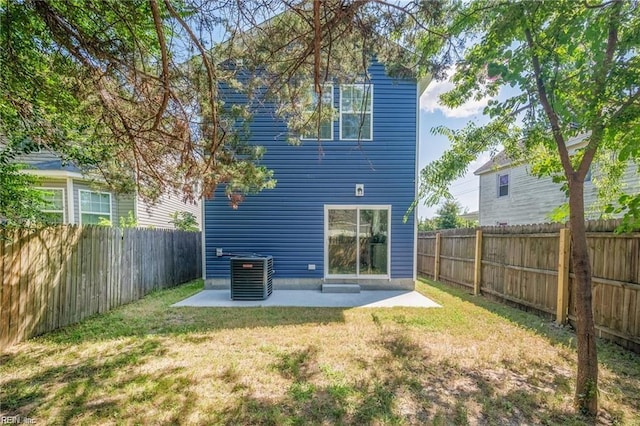 rear view of house with central air condition unit, a patio area, and a yard