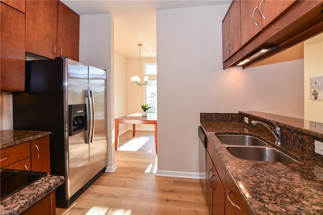 kitchen featuring hanging light fixtures, sink, appliances with stainless steel finishes, light hardwood / wood-style floors, and a chandelier