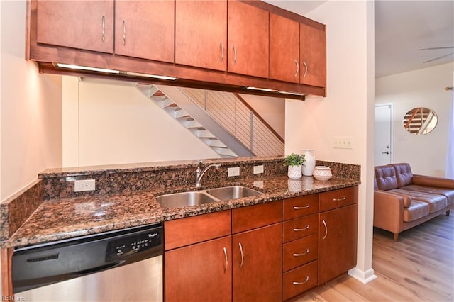 kitchen with light hardwood / wood-style floors, stainless steel dishwasher, dark stone counters, and sink