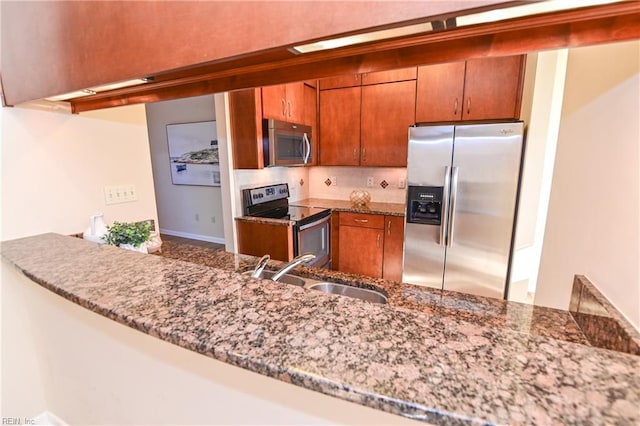 kitchen featuring stone counters, stainless steel appliances, kitchen peninsula, and sink