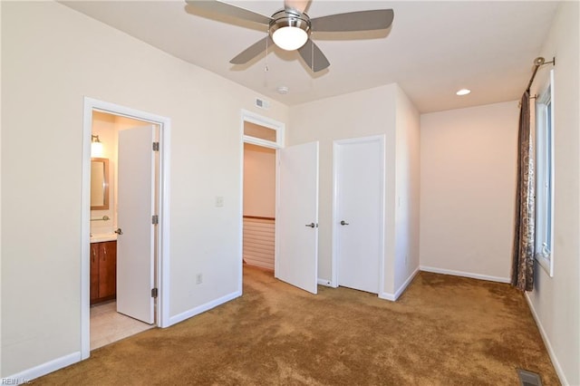 unfurnished bedroom with ceiling fan, ensuite bathroom, light carpet, and a closet