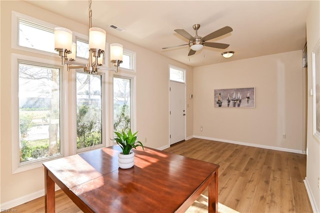 dining space with wood-type flooring and ceiling fan with notable chandelier