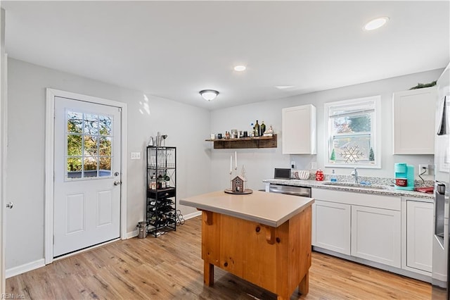 kitchen featuring a wealth of natural light, white cabinetry, light hardwood / wood-style flooring, and a center island