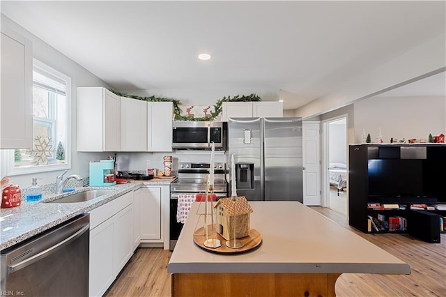 kitchen featuring sink, light wood-type flooring, a kitchen island, white cabinetry, and stainless steel appliances