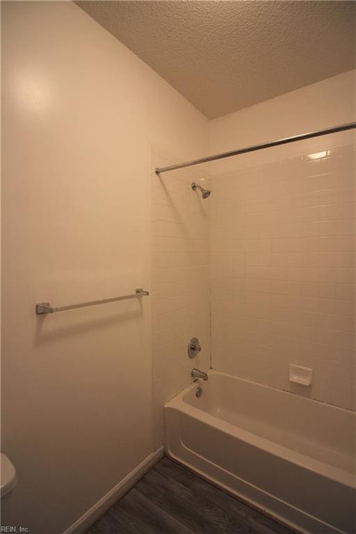 bathroom featuring hardwood / wood-style floors, a textured ceiling, toilet, and tiled shower / bath