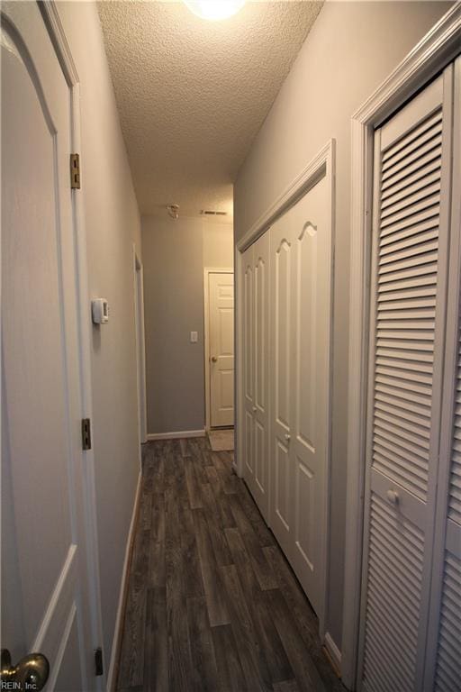 hall with dark wood-type flooring and a textured ceiling