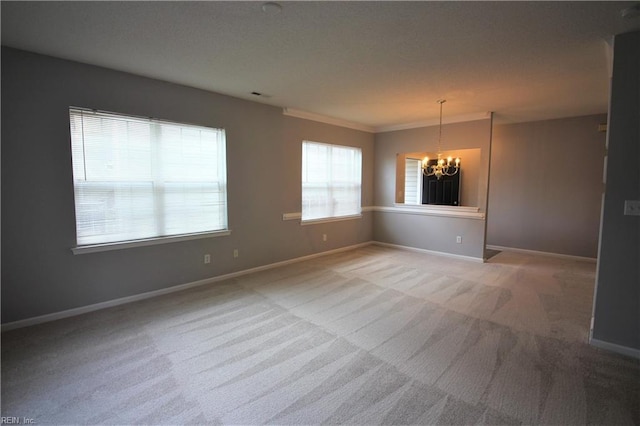 spare room with carpet floors, ornamental molding, and a chandelier