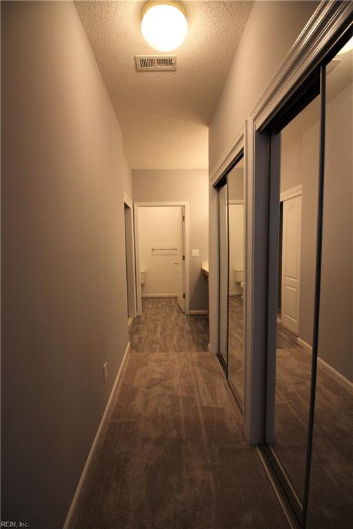 hall featuring carpet floors and a textured ceiling