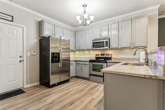 kitchen featuring sink, light hardwood / wood-style flooring, decorative light fixtures, gray cabinets, and appliances with stainless steel finishes