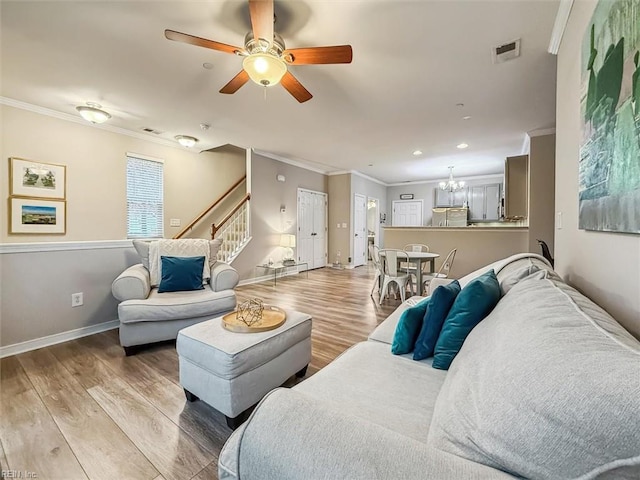 living room featuring ceiling fan with notable chandelier, light hardwood / wood-style floors, and ornamental molding