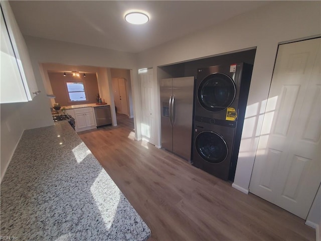 laundry area featuring stacked washer / dryer and hardwood / wood-style floors