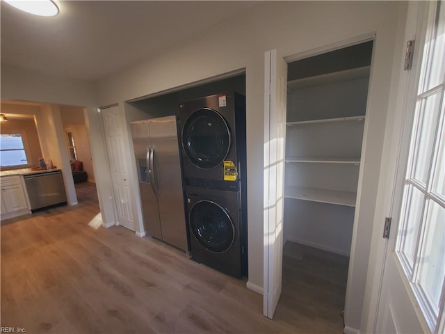 washroom with light hardwood / wood-style floors and stacked washer / drying machine