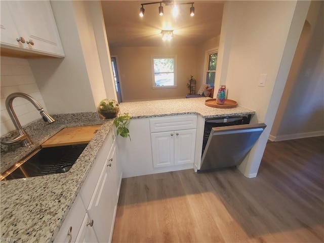 kitchen with white cabinetry, sink, light stone counters, and stainless steel dishwasher