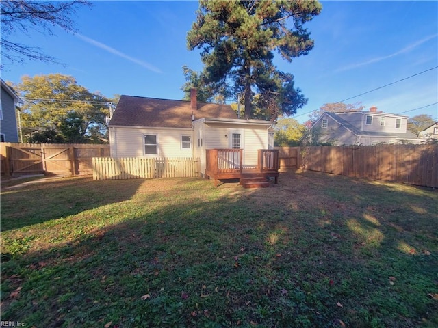 back of house featuring a lawn and a wooden deck